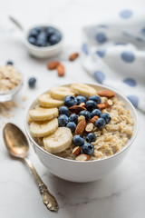Oatmeal porridge with blueberries, almonds and banana on marble table