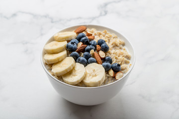 Oatmeal porridge with blueberries, almonds and banana on marble table