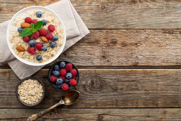 Oatmeal with raspberries, almonds and blueberries and mint on old wood background