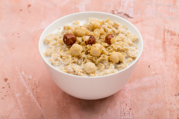 Oatmeal with hazelnut and honey on pink background
