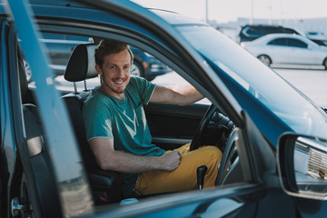 Naklejka premium Handsome young man in shirt sitting in the car