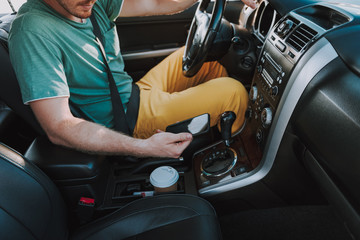 Young man in shirt using cellphone in auto