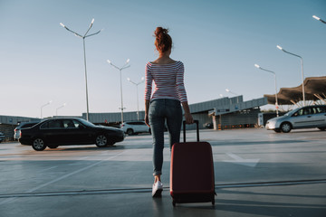 Young woman with travel suitcase walking in airport