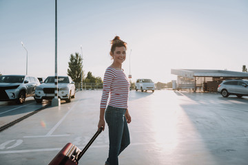 Beautiful young woman with travel suitcase standing in airport
