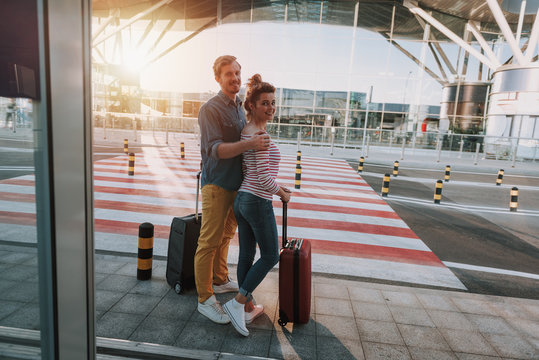 Beautiful couple with travel suitcases standing in airport
