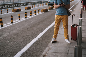 Young man with travel bag using cellphone on the street