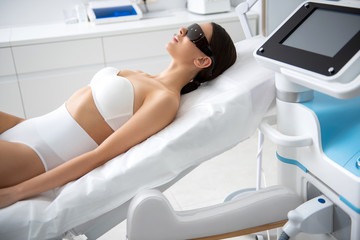 Young lady lying in laser cosmetic center