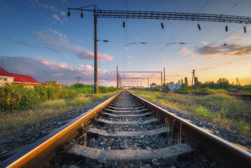 Railway station and beautiful sky at sunset. Summer rural industrial landscape with railroad, blue sky with colorful clouds and green grass at dusk. Railway junction. Transportation. Heavy industry