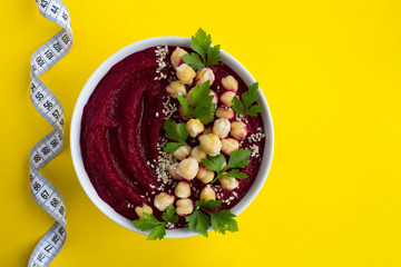 Vegan smoothies bowl with beetroot,chickpea and  white centimeter on the yellow background.Top view.Copy space.