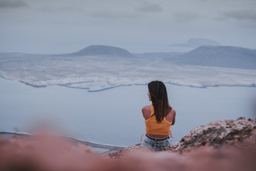 Chica sentada de espaldas mirando a la isla de La Graciosa desde el Mirador del Río