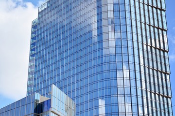 New office building in business center. Wall made of steel and glass with blue sky. 