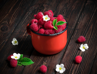 Fresh ripe organic raspberry in a mug on a wooden background