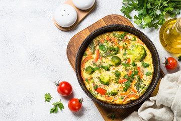 Frittata with vegetables on white stone table.