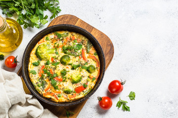 Frittata with vegetables on white stone table.