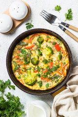 Frittata with vegetables on white stone table.