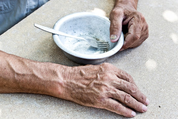 Hungry. Poor old man's hands an empty bowl. Selective focus. Poverty in retirement. Alms