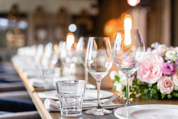 Wine glasses in the foreground. Wedding Banquet or gala dinner. The chairs and table for guests, served with cutlery and crockery.