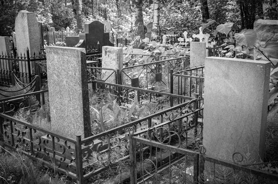 In the old cemetery there are graves with tombstones and crosses. Black and white image.