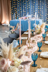 luxury dinner Banquet in the restaurant. Beautiful and exquisite decoration of the wedding celebration. Banquet served table with a beige pink tablecloth, plates and candlesticks with candles.