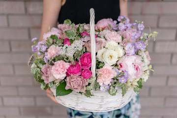 Flower arrangement in Wicker basket. Beautiful bouquet of mixed flowers in woman hand. Floral shop...