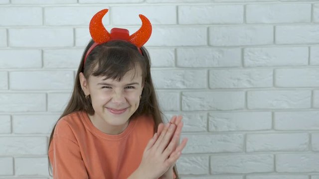A cunning child with devil horns. Sly little girl in devil horns. Cunning child.