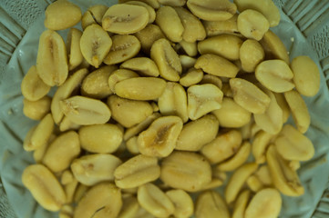 Peeled peanuts without husk in a glass plate on a white background close-up