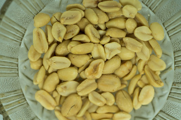 Peeled peanuts without husk in a glass plate on a white background close-up