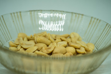 Peeled peanuts without husk in a glass plate on a white background close-up