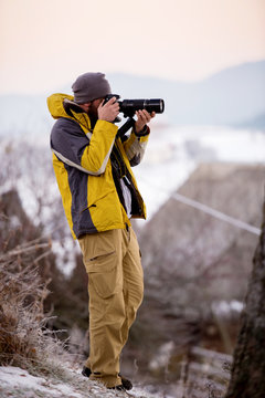 male photographer taking photographs of winter forest