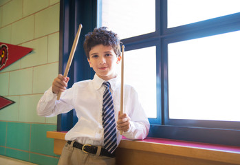 School boy (10-11) holding drumsticks in classroom © Cavan for Adobe