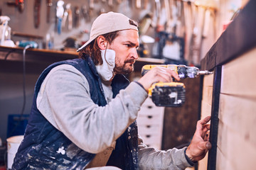 Male carpenter working on old wood in a retro vintage workshop.