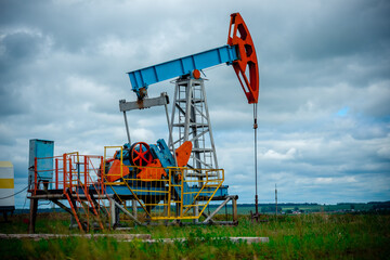 Fototapeta na wymiar Oil field with pump jack, profiled on blue sky with white clouds, on a sunny day in spring
