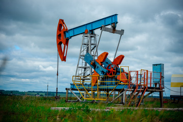 Fototapeta na wymiar Oil field with pump jack, profiled on blue sky with white clouds, on a sunny day in spring
