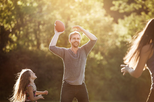 Man playing football with his children (4-5) in backyard