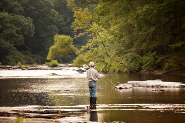 Fototapeta premium Rear view of senior man fishing in river