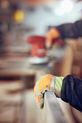 Carpenter using orbital electric sander in a retro vintage workshop.