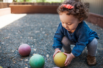 Fototapeta premium Little girl playing with balls outdoors