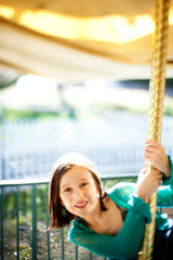 Obraz premium Young girl (8-9) smiling on carousel