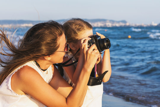 Summer holidays: mother and daughter take pictures of sights while walking near the sea