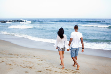 Obraz premium Young couple walking on beach holding hands