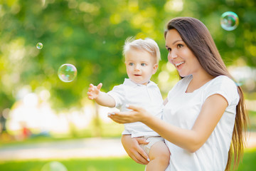 Happy family, Young mother and baby son blowing soap bubbles outdoor park