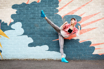 New York State,Woman kicking leg up in front of graffiti wall © Cavan for Adobe