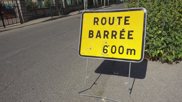 "Closed road" - "Route barrée" sign in France. Seasonal road repair works in city. No people or cars.