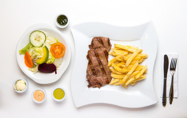 Beef and french fries with salad and creams. Top view.
