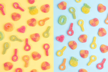Multicolored gummy candies on yellow and blue backgrounds. Top view.