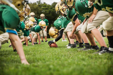 Boys playing American football in field © Cavan for Adobe