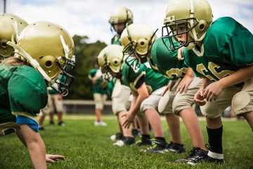 Boys playing American football in field © Cavan for Adobe