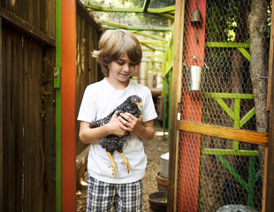 Boy holding chicken in chicken coop © Cavan for Adobe