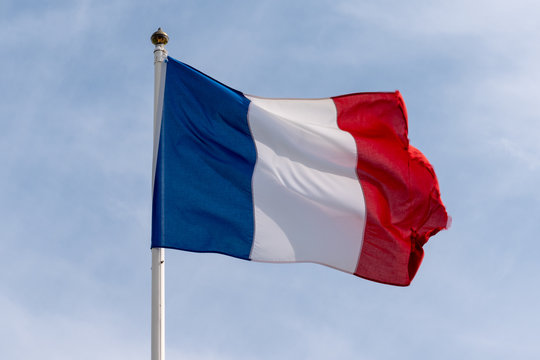 french flag of France waving over cloudy blue sky blue white red colors