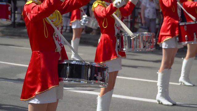 Young girls drummer in red at the parade. Close-up of female hands drummers are knocking in the drum of their sticks